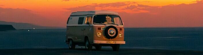 A classic van watches the sunset over the sea.